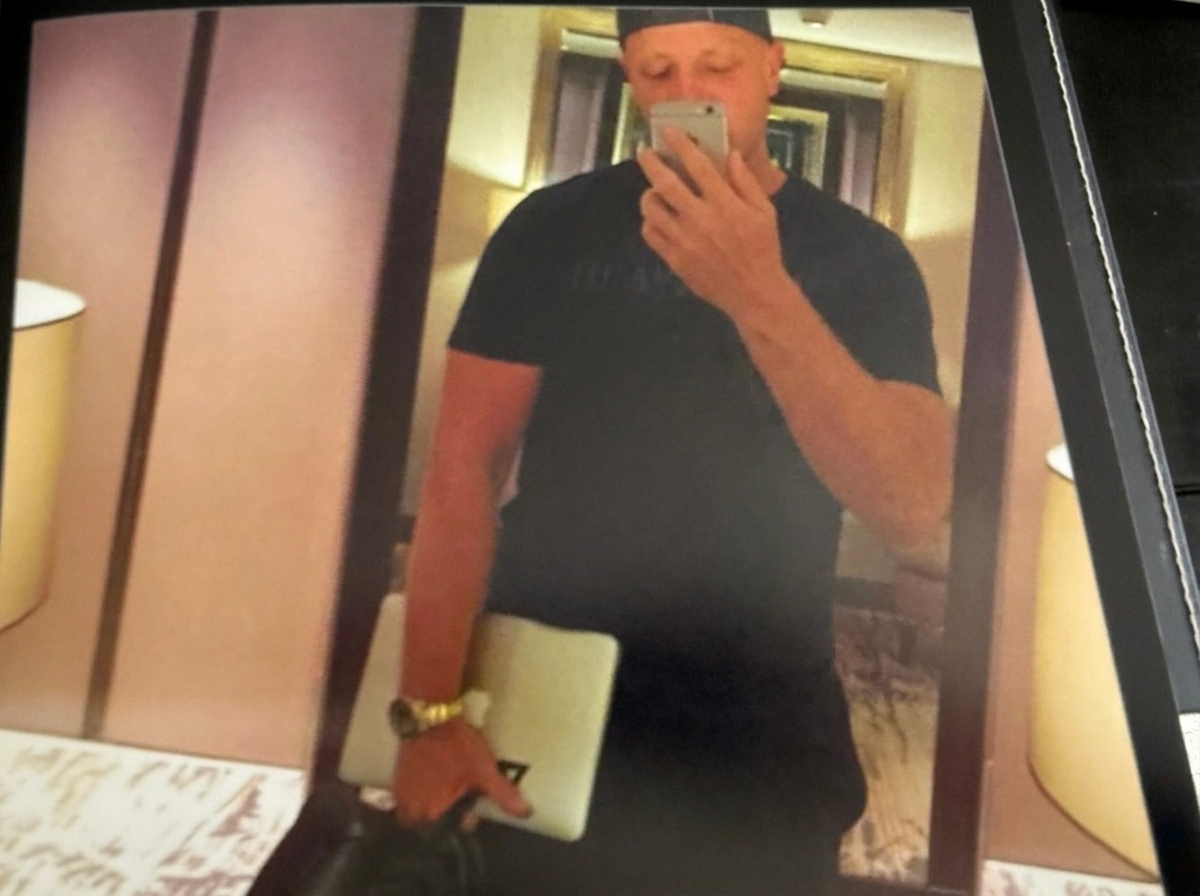 Spiegelselfie met MacBook en gouden horloge in een hotelgang.