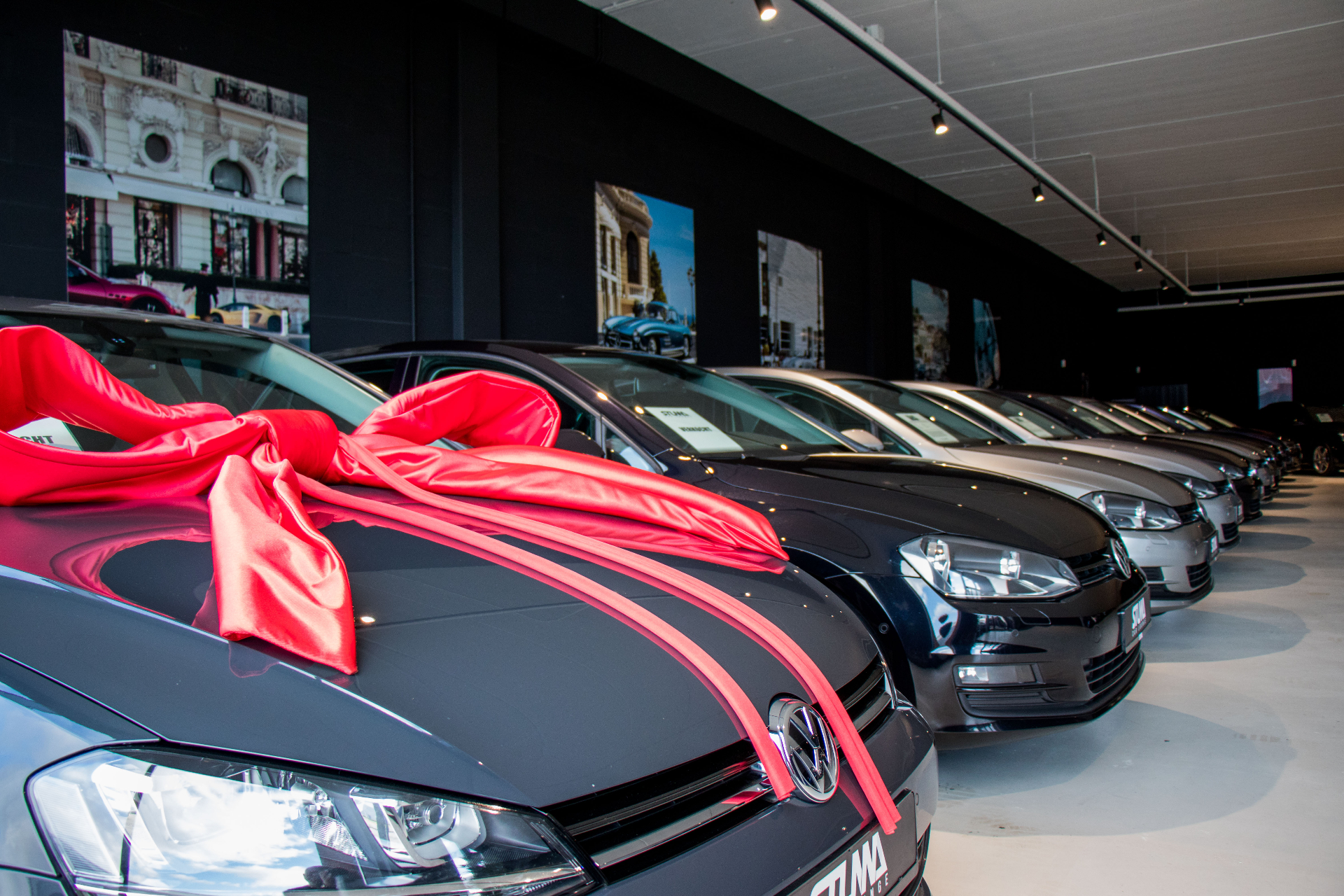 Rij auto's in de Stunna showroom met rode strik op de voorste.